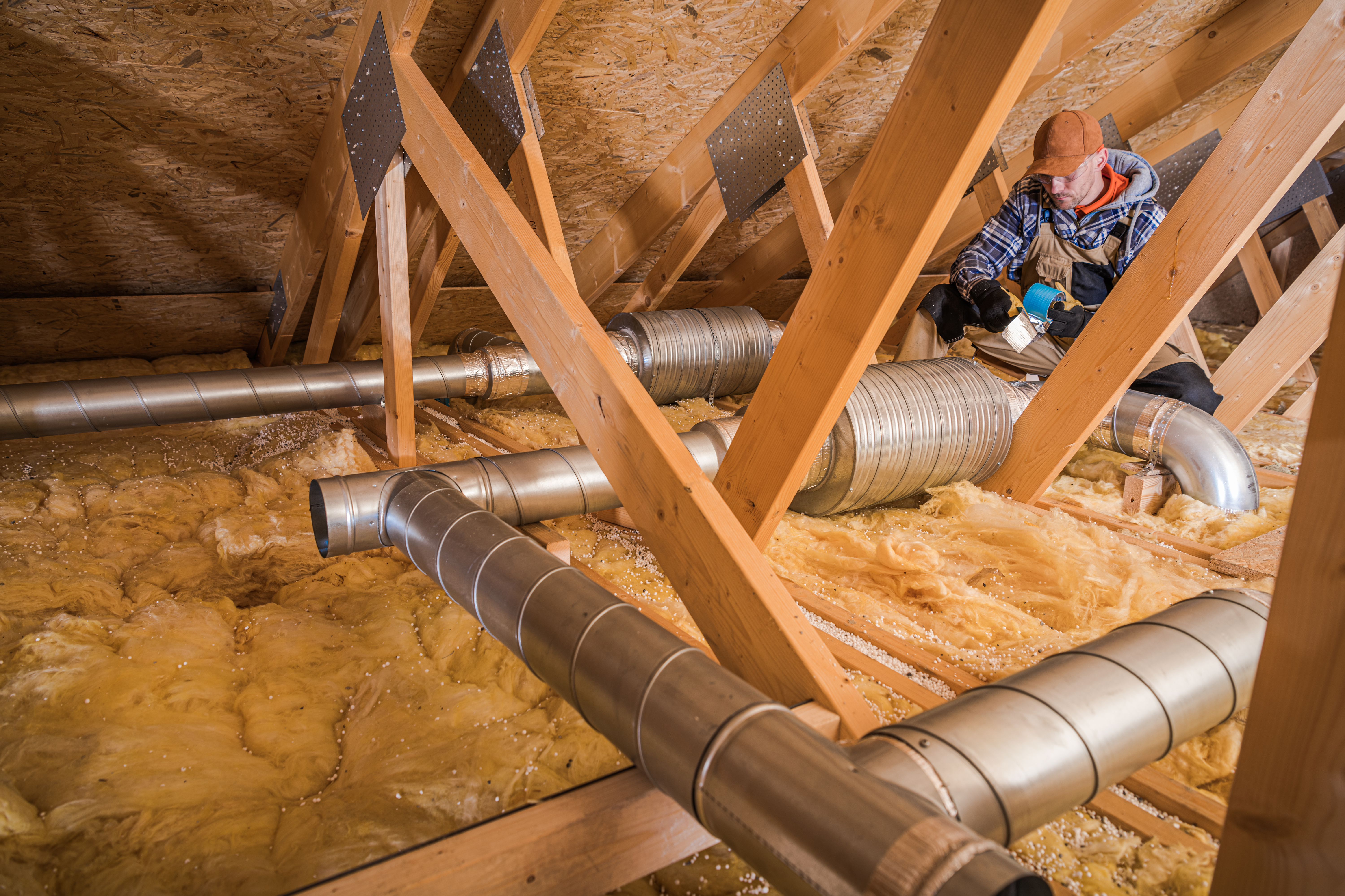 HVAC technician working on ductwork in a residential attic